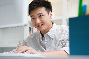 Young Asian man looking at computer screen