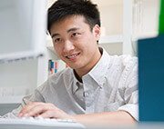 Young Asian man looking at computer screen
